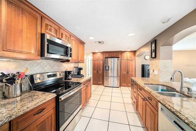 kitchen with light tile patterned floors, visible vents, light stone counters, stainless steel appliances, and a sink