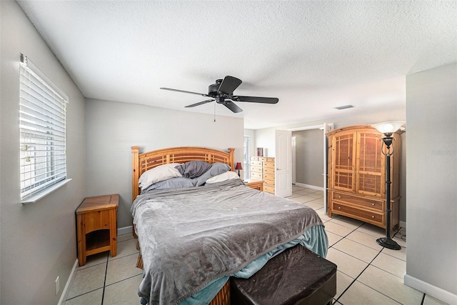 bedroom with light tile patterned floors, baseboards, visible vents, ceiling fan, and a textured ceiling