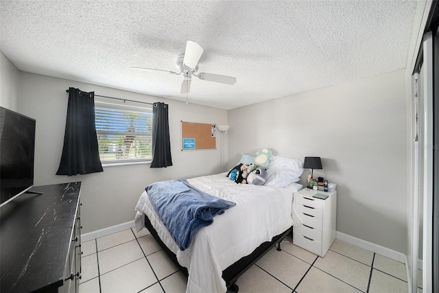 bedroom with a textured ceiling, baseboards, a ceiling fan, and light tile patterned flooring