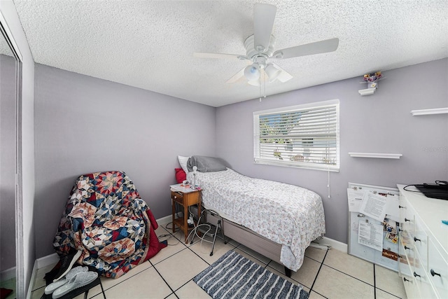 bedroom with a ceiling fan, light tile patterned flooring, a textured ceiling, and baseboards