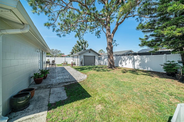 view of yard featuring a garage, a fenced backyard, an outbuilding, and a patio