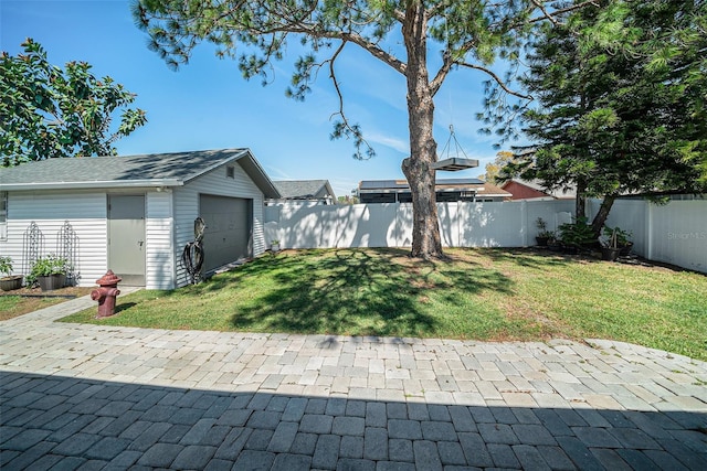 view of yard featuring a garage, a patio area, a fenced backyard, and an outdoor structure