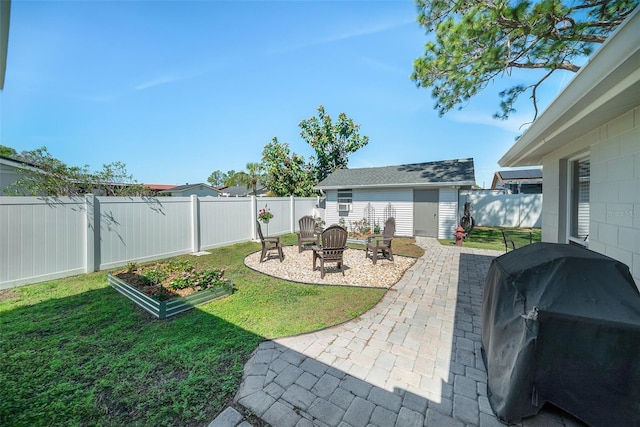 view of yard with a vegetable garden, a patio area, a fenced backyard, an outdoor structure, and a fire pit