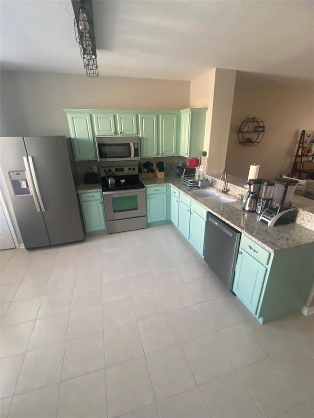 kitchen featuring tasteful backsplash, appliances with stainless steel finishes, a peninsula, a sink, and green cabinetry