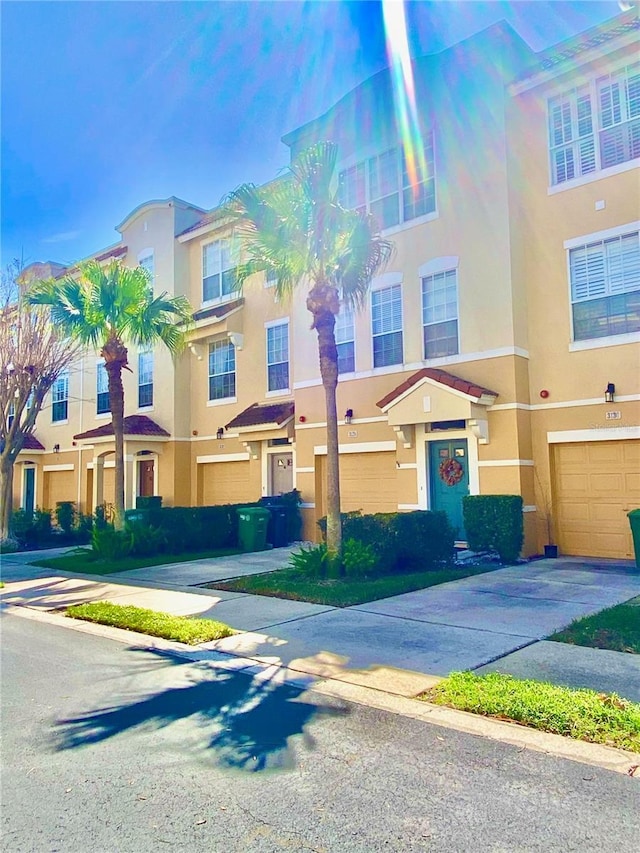 multi unit property featuring a garage, driveway, and stucco siding