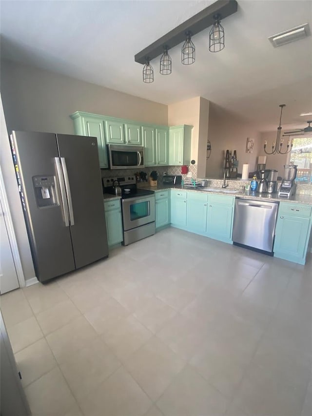 kitchen featuring visible vents, backsplash, appliances with stainless steel finishes, a sink, and a peninsula