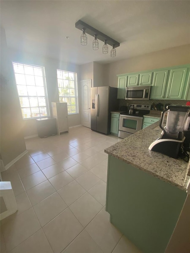 kitchen featuring decorative backsplash, green cabinetry, appliances with stainless steel finishes, a sink, and light tile patterned flooring