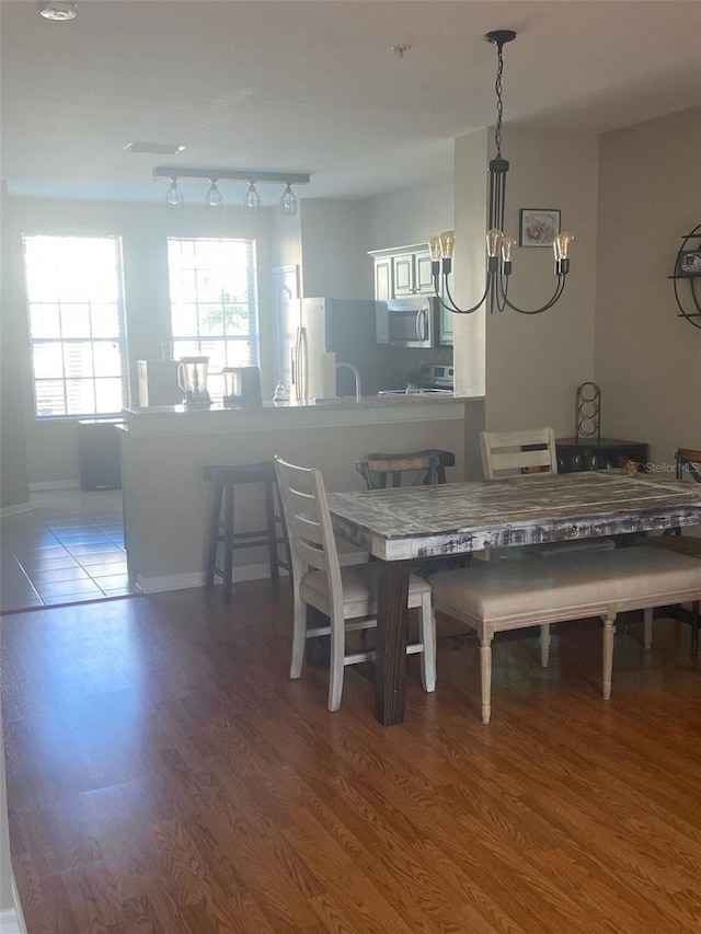 dining area with an inviting chandelier, track lighting, and wood finished floors