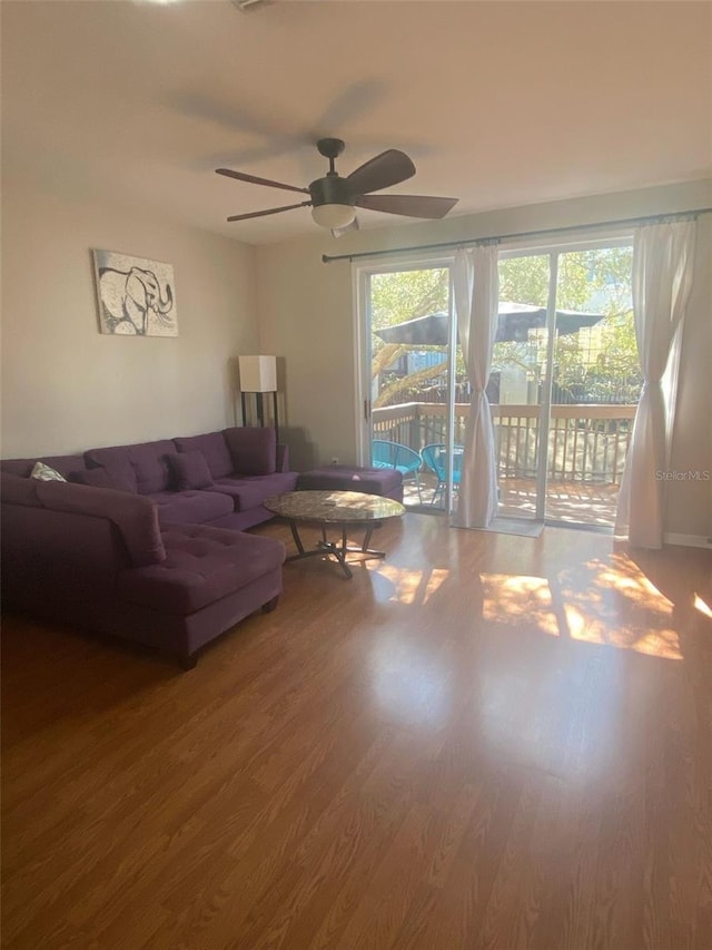 living room featuring ceiling fan, wood finished floors, and a wealth of natural light