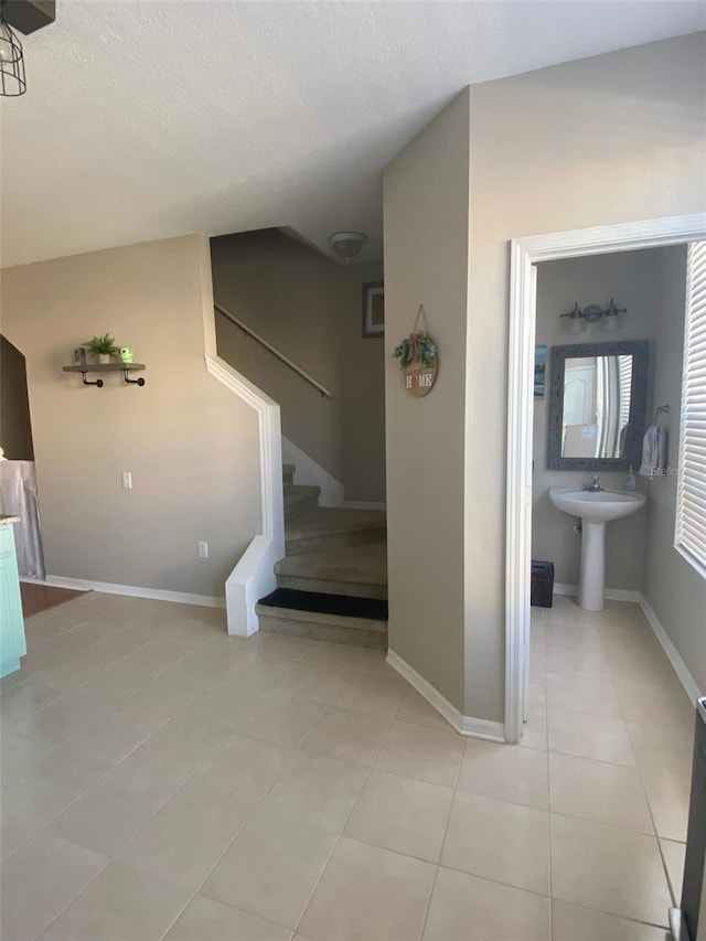 staircase featuring baseboards, a textured ceiling, and tile patterned floors