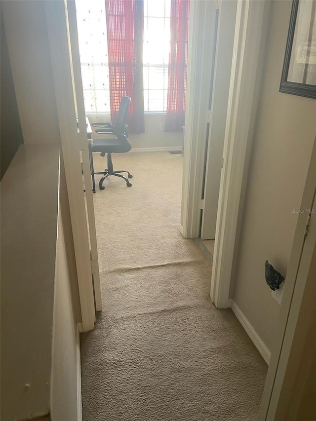 hallway featuring carpet and baseboards