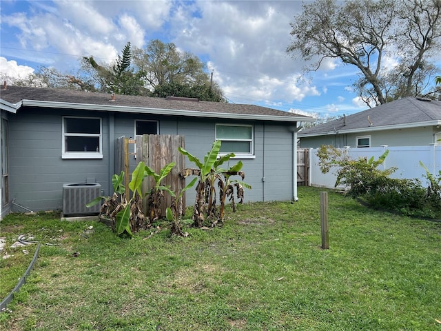 back of property featuring fence, central AC unit, and a lawn