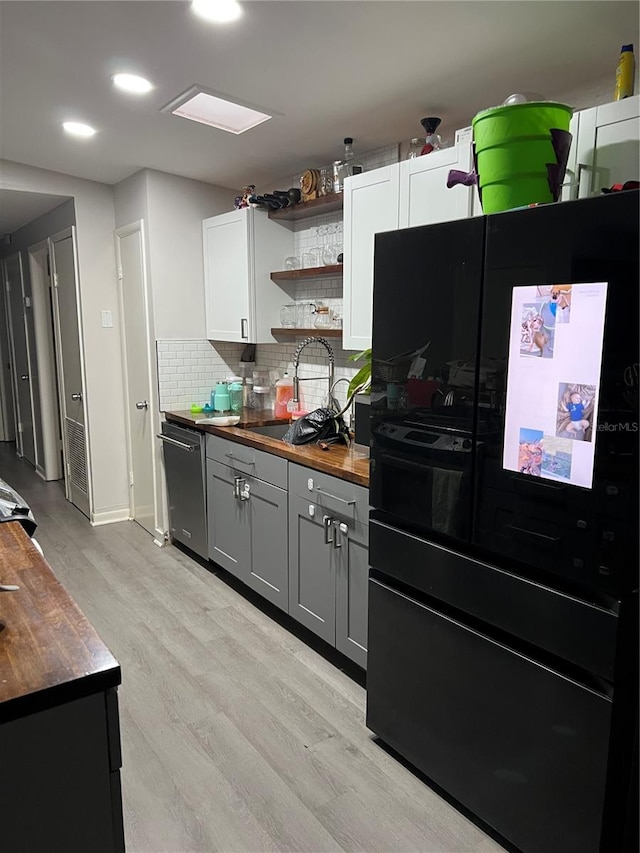 kitchen with open shelves, butcher block countertops, a sink, and freestanding refrigerator