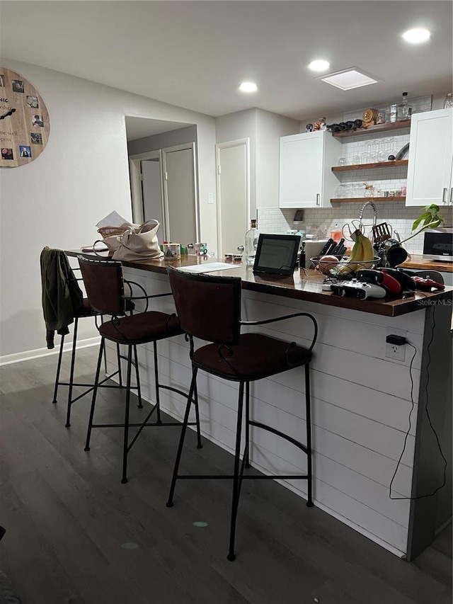 kitchen featuring a breakfast bar area, wood finished floors, white cabinets, decorative backsplash, and open shelves