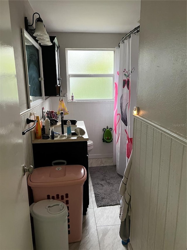 bathroom with curtained shower, toilet, wooden walls, vanity, and tile patterned floors