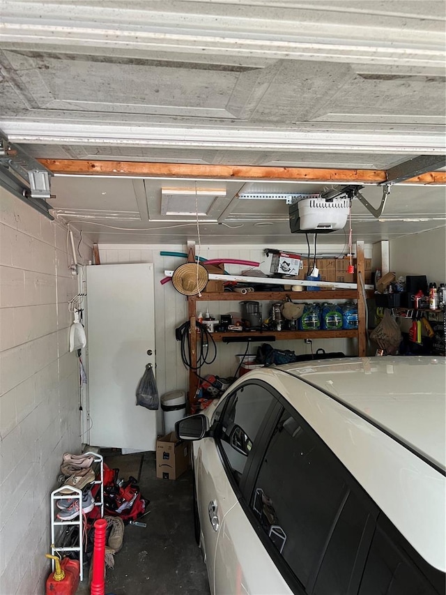 garage featuring a garage door opener and concrete block wall