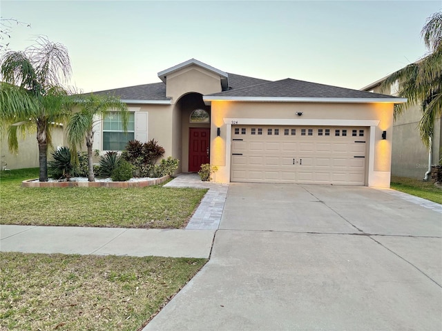 ranch-style home with an attached garage, a shingled roof, driveway, stucco siding, and a front lawn