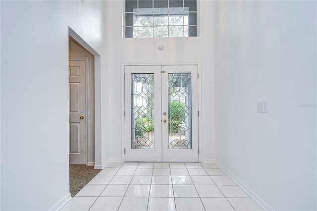 entryway with french doors, a towering ceiling, and baseboards