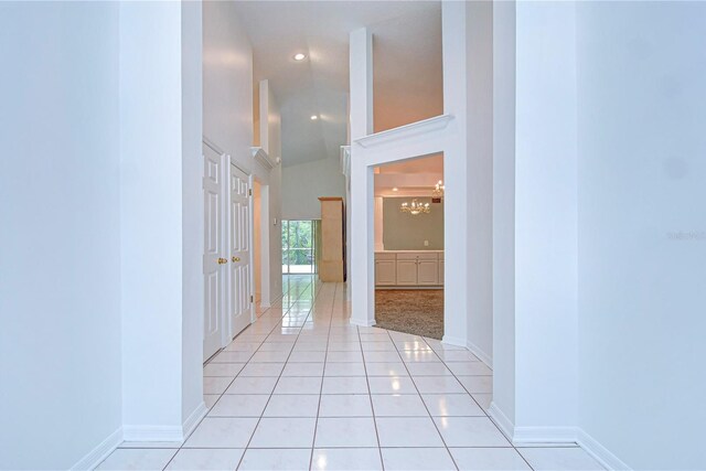 hall featuring recessed lighting, baseboards, vaulted ceiling, and light tile patterned flooring