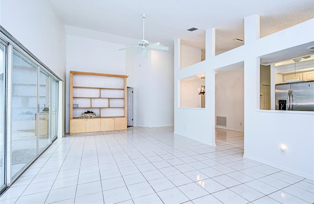 empty room featuring light tile patterned floors, ceiling fan, visible vents, and high vaulted ceiling