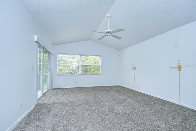 carpeted empty room with a textured ceiling, baseboards, vaulted ceiling, and a wealth of natural light