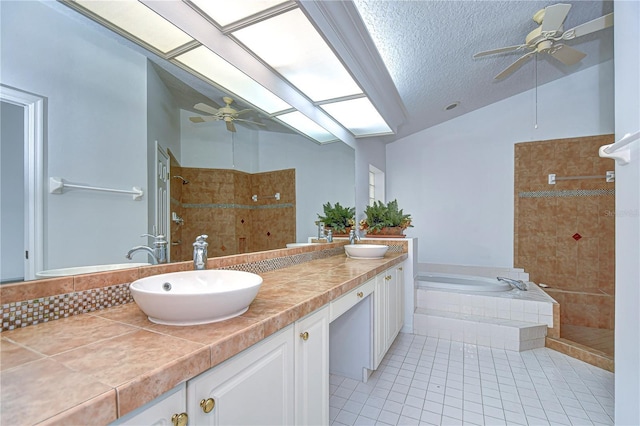 full bathroom with lofted ceiling with skylight, tiled shower, a sink, and a garden tub