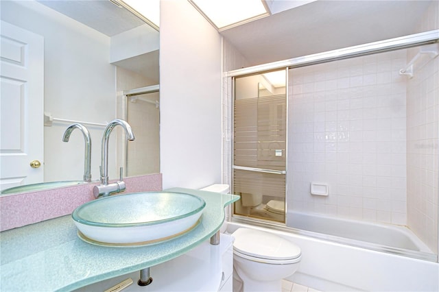 full bathroom with bath / shower combo with glass door, vanity, and toilet