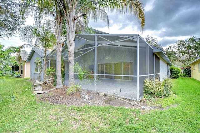 view of side of home featuring glass enclosure, stucco siding, a lawn, and a patio