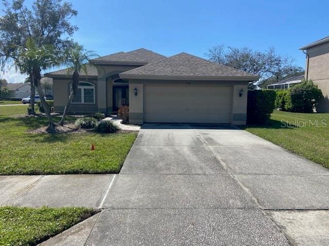 view of front of house with a front lawn, concrete driveway, and stucco siding