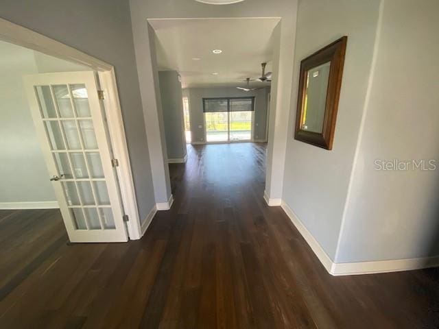 corridor featuring baseboards and dark wood-type flooring