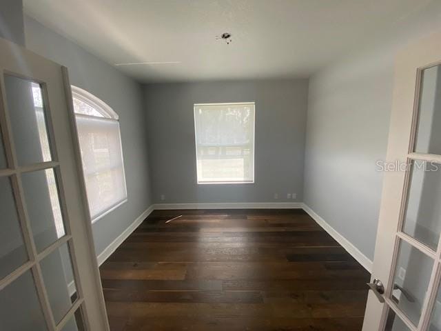 spare room featuring baseboards and wood finished floors