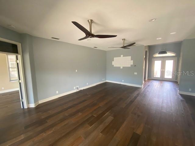 spare room featuring french doors, visible vents, dark wood-type flooring, a ceiling fan, and baseboards