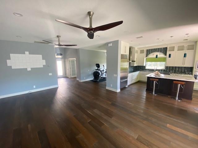 kitchen with backsplash, open floor plan, white cabinetry, stainless steel built in fridge, and a kitchen bar