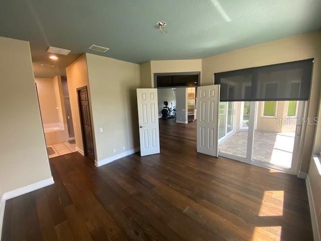 spare room with wood finished floors, visible vents, and baseboards