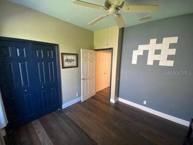 unfurnished bedroom featuring ceiling fan, visible vents, baseboards, and dark wood finished floors