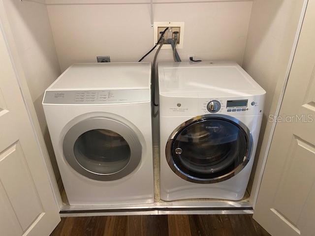 washroom featuring laundry area, independent washer and dryer, and dark wood-style flooring