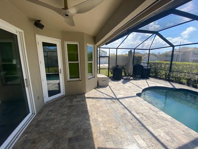 view of pool with a lanai, a patio area, and ceiling fan