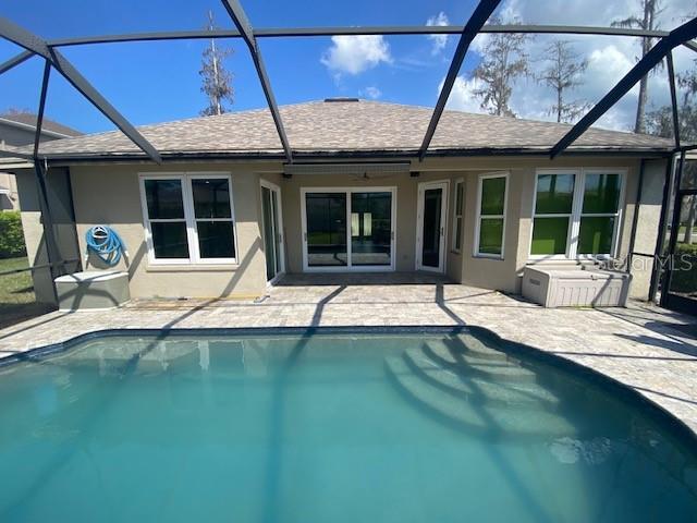 back of house featuring a shingled roof, a patio area, an outdoor pool, and stucco siding