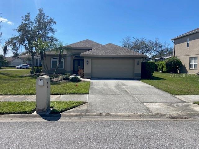 view of front facade featuring concrete driveway, a front lawn, an attached garage, and stucco siding