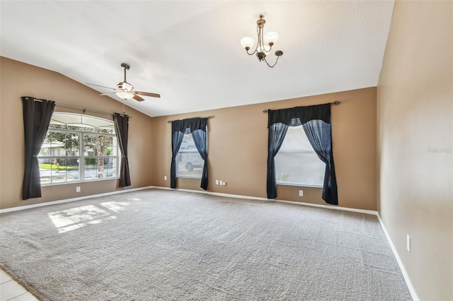 carpeted spare room with lofted ceiling, ceiling fan with notable chandelier, a wealth of natural light, and baseboards