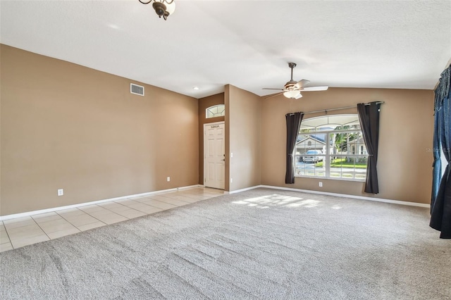 carpeted spare room with lofted ceiling, a ceiling fan, baseboards, visible vents, and tile patterned floors