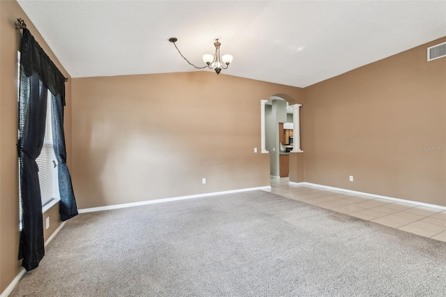 spare room with arched walkways, light tile patterned floors, a chandelier, light carpet, and vaulted ceiling