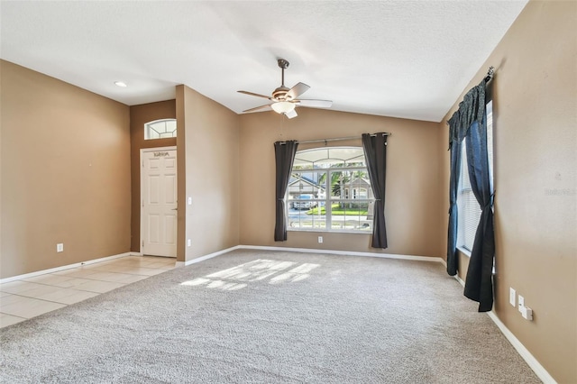 empty room with light carpet, baseboards, vaulted ceiling, and light tile patterned flooring