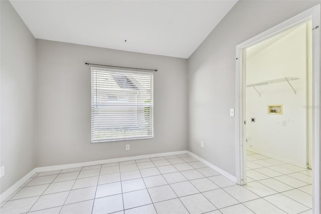 unfurnished room with lofted ceiling, baseboards, and light tile patterned floors