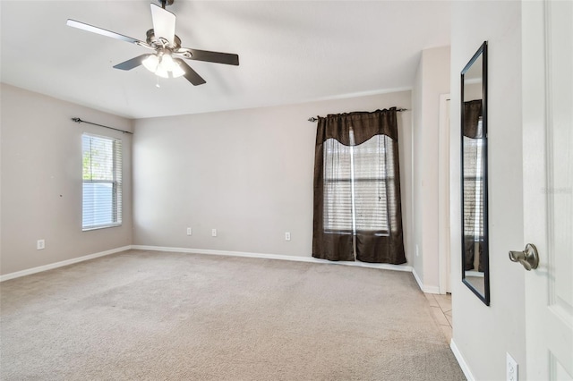 spare room with light carpet, ceiling fan, and baseboards