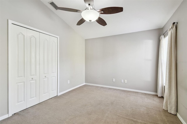 unfurnished bedroom featuring lofted ceiling, a closet, carpet flooring, ceiling fan, and baseboards