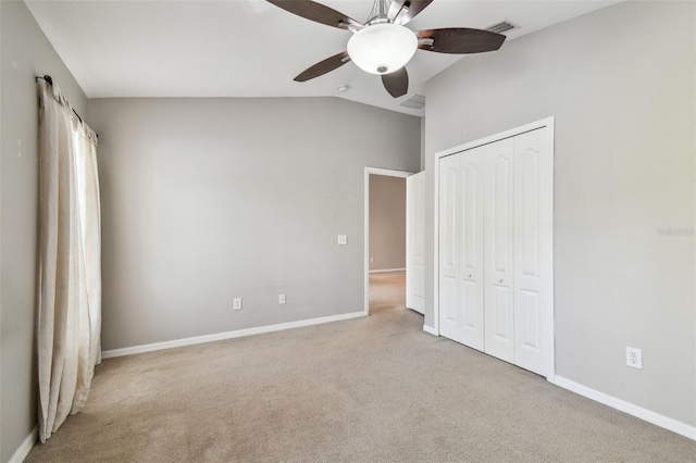 unfurnished bedroom with carpet, a closet, visible vents, vaulted ceiling, and baseboards