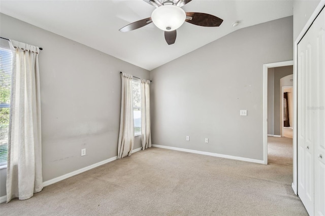 unfurnished room featuring lofted ceiling, carpet, baseboards, and a ceiling fan