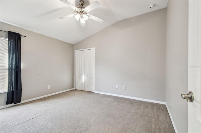 carpeted spare room featuring lofted ceiling, ceiling fan, and baseboards