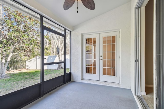 unfurnished sunroom featuring lofted ceiling, a ceiling fan, and french doors